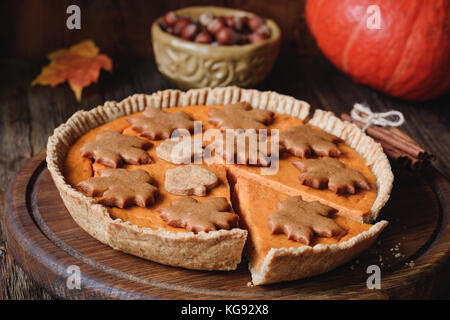 Tarte au potiron entier avec noix de pécan et gingerbread cookies sur planche de bois. vue rapprochée, horizontal Banque D'Images