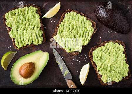 Toast à l'avocat en bonne santé. la purée d'avocat sur pain de seigle à grains entiers sur fond sombre. Vue de dessus la nourriture végane Banque D'Images