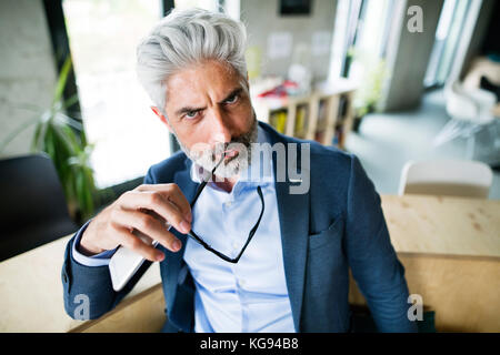 Mature businessman en costume bleu dans le bureau. Banque D'Images