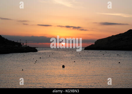 Coucher de soleil sur la mer Méditerranée, comme vu de la station balnéaire de Xlendi à Gozo, Malte Banque D'Images