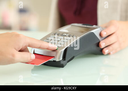 Close up d'un client entrant dans un lecteur de carte de crédit sur un comptoir dans un magasin Banque D'Images