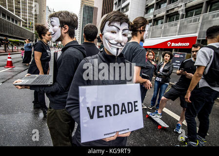 Sao Paulo, Brésil. 5Th nov, 2017. Des militants de l'organisation pour les sans-voix anonyme, se tiennent près de l'avenue Paulista comme ils portent des masques et maintenez-écrans pour afficher des vidéos à partir de la viande, des œufs et des industries, le 5 novembre 2017. Le groupe prend en charge un style de vie vegan, et les protestations contre la violence envers les animaux dans les secteurs d'activités susmentionnés. crédit : cris faga/zuma/Alamy fil live news Banque D'Images