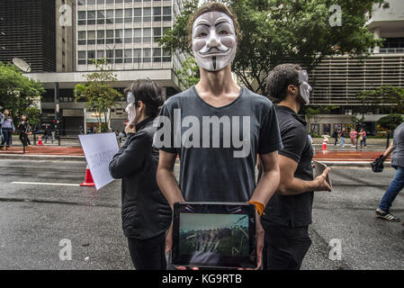 Sao Paulo, Brésil. 5 novembre 2017. Des activistes de l'organisation Anonymous for the Voiceless se tiennent près de l'avenue Paulista alors qu'ils portent des masques et tiennent des écrans affichant des vidéos des industries de la viande, des œufs et de la fourrure, le 5 novembre 2017. Le groupe soutient un style de vie végétalien et proteste contre la maltraitance des animaux dans les industries mentionnées. Crédit : cris Faga/ZUMA Wire/Alamy Live News Banque D'Images