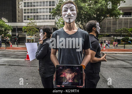 Sao Paulo, Brésil. 5Th nov, 2017. Des militants de l'organisation pour les sans-voix anonyme, se tiennent près de l'avenue Paulista comme ils portent des masques et maintenez-écrans pour afficher des vidéos à partir de la viande, des œufs et des industries, le 5 novembre 2017. Le groupe prend en charge un style de vie vegan, et les protestations contre la violence envers les animaux dans les secteurs d'activités susmentionnés. crédit : cris faga/zuma/Alamy fil live news Banque D'Images