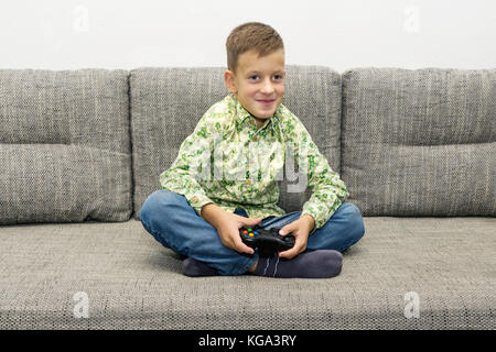 Les loisirs, les enfants, les hommes et la technologie concept - smiling boy avec manette de jeu vidéo à la maison de jeu Banque D'Images