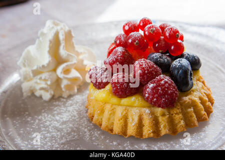 Petite tartelette, dessert avec des bleuets, des framboises et de la crème. Banque D'Images