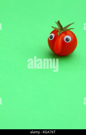 Tomate cerise mûre fraîche avec un visage sur un fond uni avec copie espace Banque D'Images