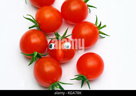 Tomate cerise mûre fraîche avec un visage sur un fond uni avec copie espace Banque D'Images