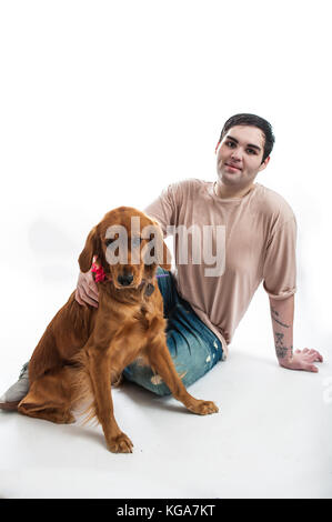 L'homme à peau claire partagé un moment avec son golden retriever sur le sol. Banque D'Images