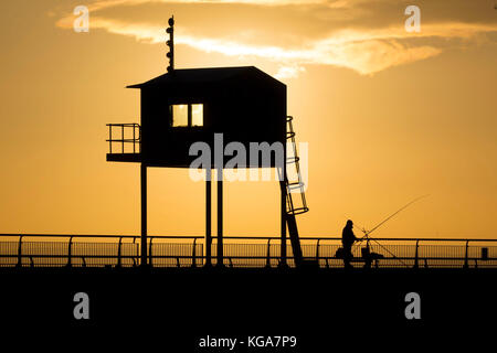 Un pêcheur regarde le soleil se lève sur la baie de Cardiff, Cardiff, Pays de Galles en barrage. Les prévisionnistes ont prédit une semaine de froid qui a été proposée à Banque D'Images