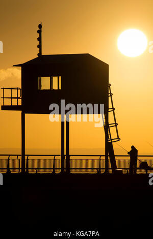 Un pêcheur regarde le soleil se lève sur la baie de Cardiff, Cardiff, Pays de Galles en barrage. Les prévisionnistes ont prédit une semaine de froid qui a été proposée à Banque D'Images
