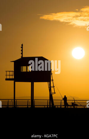 Un pêcheur regarde le soleil se lève sur la baie de Cardiff, Cardiff, Pays de Galles en barrage. Les prévisionnistes ont prédit une semaine de froid qui a été proposée à Banque D'Images