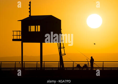 Un pêcheur regarde le soleil se lève sur la baie de Cardiff, Cardiff, Pays de Galles en barrage. Les prévisionnistes ont prédit une semaine de froid qui a été proposée à Banque D'Images