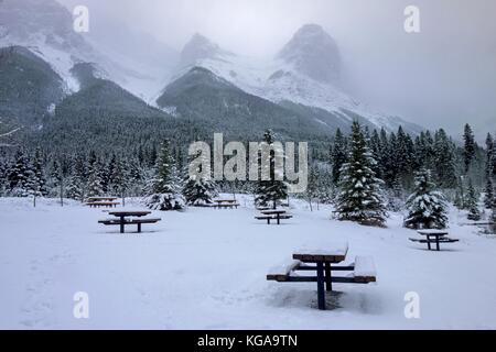 Table d'aire de pique-nique couverte de neige, paysage forestier d'hiver pittoresque. Pics nuageux des montagnes Rocheuses, parc provincial Kananaskis, Canmore Alberta Canada Banque D'Images