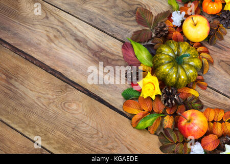 Vert l'action de la citrouille, pommes, pommes de pin, feuilles d'automne coloré, des roses jaunes couronne sur le fond en bois rustique, copy space Banque D'Images