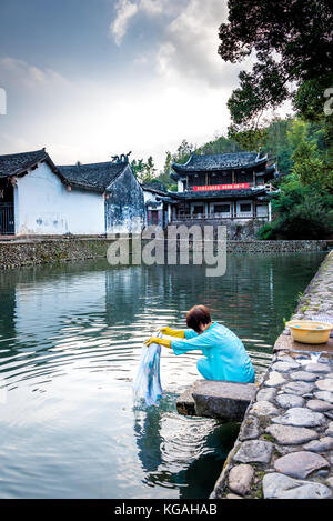 Une femme lave-linge dans une piscine au calme de l'eau au village chinois ancien Rock Town par Shanghai Street, Yongjia County, Zhejiang, Chine Banque D'Images