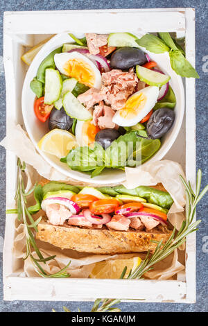 Le déjeuner avec du thon : salade et sandwich dans une boîte en bois. panier repas à emporter, concept. Banque D'Images