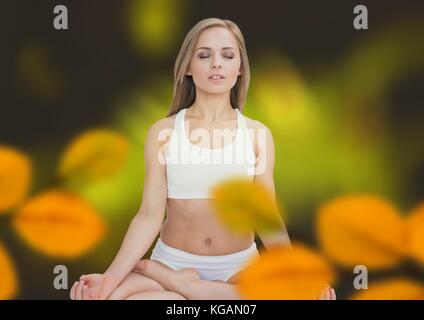 Digital composite of Woman meditating in forest avec feuilles Banque D'Images