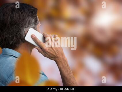 Digital composite de l'homme sur le téléphone en forêt avec des feuilles Banque D'Images