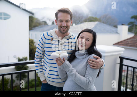 Femme enceinte et son mari holding Baby socks en balcon à la maison Banque D'Images