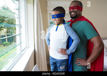 Smiling père et fils en costume de super-héro à la fenêtre grâce à à la maison Banque D'Images