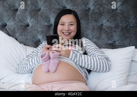 Portrait de femme à l'aide de mobile avec paire de chaussettes sur son estomac Banque D'Images