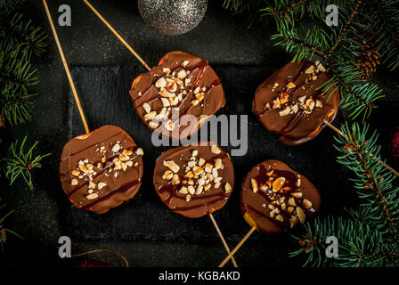 Des idées de l'hiver, Noël des bonbons pour les enfants.. chocolat tranches de pomme dans le chocolat, avec un caramel et noix. pierre vert foncé, fond wit Banque D'Images