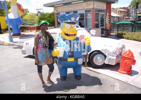 Femme afro-caribéenne posant à côté de la statue du chef Clancy Wiggum aux studios Universal Banque D'Images