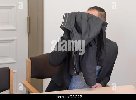 Hambourg, Allemagne. 6 novembre 2017. L'accusé de vol qualifié grave couvre son visage avec une veste pendant le procès dans le bâtiment de la justice pénale à Hambourg, Allemagne, 6 novembre 2017. L'enfant de 30 ans a volé une femme chez elle avec un autre homme tout en étant déguisé comme messager DHL le 2015 novembre. Crédit : Axel Heimken/dpa/Alay Live News Banque D'Images