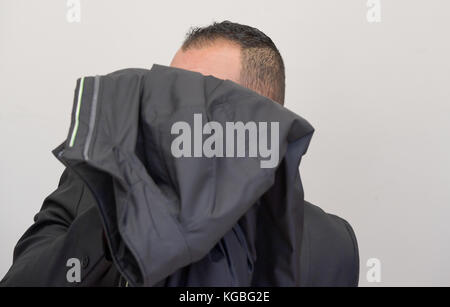 Hambourg, Allemagne. 6 novembre 2017. L'accusé de vol qualifié grave couvre son visage avec une veste pendant le procès dans le bâtiment de la justice pénale à Hambourg, Allemagne, 6 novembre 2017. L'enfant de 30 ans a volé une femme chez elle avec un autre homme tout en étant déguisé comme messager DHL le 2015 novembre. Crédit : Axel Heimken/dpa/Alay Live News Banque D'Images