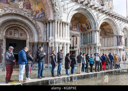 Venise, Vénétie, Italie. 6Th Nov 2017. Acqua Alta marée haute à partir de la lagune provoquant des inondations temporaires sur la Piazza San Marco. Passerelle, ou des passerelles, sont installés à la circulation des piétons. Les touristes faisant la queue pour entrer dans la Basilique de San Marco. Credit : Mary Clarke/Alamy Live News Banque D'Images