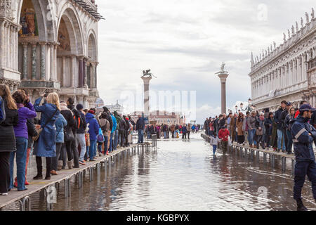 Venise, Vénétie, Italie. 6Th Nov 2017. Acqua Alta marée haute à partir de la lagune provoquant des inondations temporaires sur la Piazza San Marco. Passerelle, ou des passerelles, sont installés à la circulation des piétons. Sur la gauche est la queue pour entrer dans la Basilique de San Marco. Garde de sécurité à l'avant-plan. Credit : Mary Clarke/Alamy Live News Banque D'Images