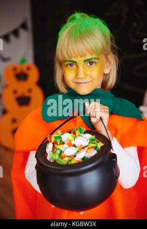 Fille en costume de citrouille tenait un bol rempli de bonbons Banque D'Images