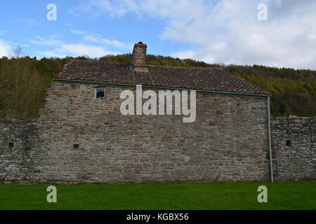 Vieux Mur de grès rouge élévation d'un bâtiment avec toit en tuiles d'argile gouttière en pente près de abbaye de tintern monmouthshire au Pays de Galles uk united kingdom Banque D'Images