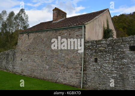 Vieux Mur de grès rouge élévation d'un bâtiment avec toit en tuiles d'argile gouttière en pente près de abbaye de tintern monmouthshire au Pays de Galles uk united kingdom Banque D'Images