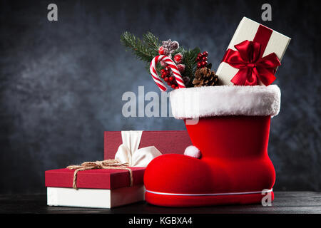 Santa's shoe avec coffrets cadeaux sur fond sombre Banque D'Images