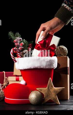 Santa's shoe avec coffrets cadeaux sur fond sombre Banque D'Images