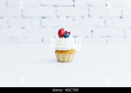 Le miel capcake avec crème au mascarpone avec des fraises et framboises bleuets. fond blanc. Banque D'Images