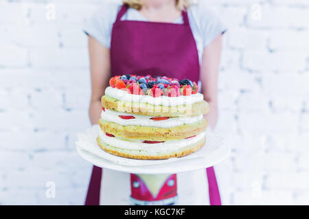 Whoopie cake sur la plaque avec les baies fraîches, women's hands holding. fond blanc. Banque D'Images