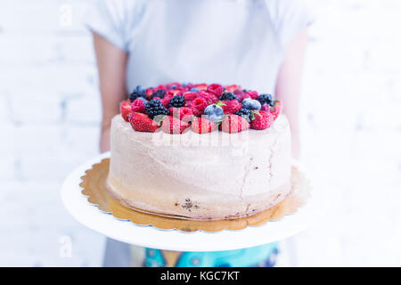 Whoopie cake sur la plaque avec les baies fraîches, women's hands holding. fond blanc. Banque D'Images