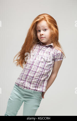 Jolie petite fille rousse en chemise à carreaux, pantalon bleu vif et blanc boots Banque D'Images