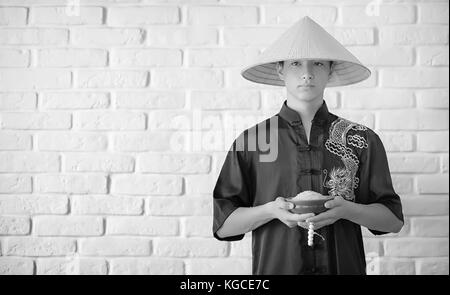 Novice asiatique sur un mur en brique blanche Banque D'Images