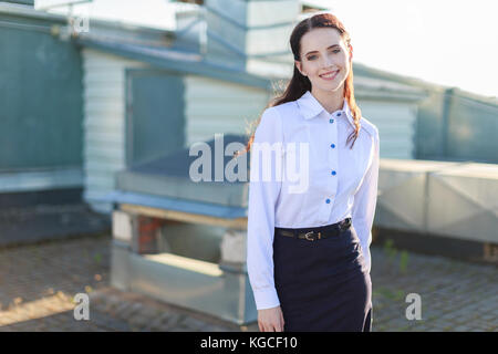 Businesslady attrayant en chemisier blanc et jupe noire debout sur le toit Banque D'Images