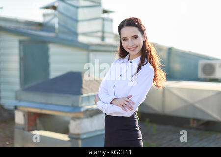 Businesslady attrayant en chemisier blanc et jupe noire debout sur le toit Banque D'Images