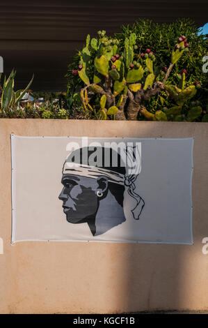 Corse : le drapeau de la Corse, une tête de maure en noir portant un foulard blanc au-dessus de ses yeux et noués sur le cou, accrochée à un mur rose à centuri Banque D'Images