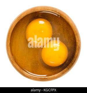 Deux oeufs de poulet cru dans un bol en bois fissuré. blanc et jaune sans coquilles. aliment commun et l'ingrédient polyvalent en cuisine. photo. Banque D'Images