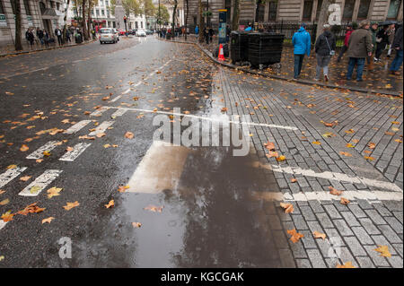 Grande flaque de pluie avec feuilles d'automne tombées à Charing Cross Road, Londres, Royaume-Uni Banque D'Images