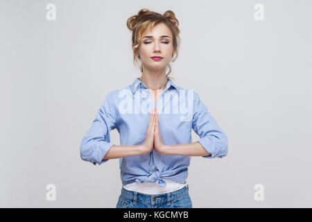 Woman holding hands in namaste ou prière, en gardant les yeux fermés tout en pratiquant le yoga et la méditation à la maison seul, avoir le calme regard sur son visage. studio Banque D'Images