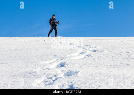 L'homme est des randonnées en raquettes dans la neige profonde sur sunny day Banque D'Images