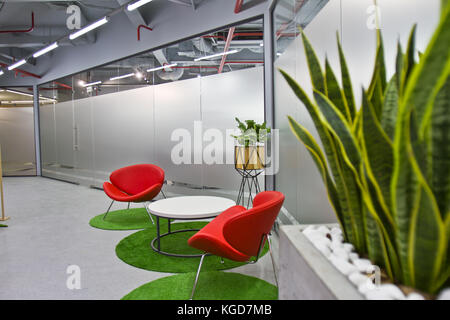 Un coin salon luxueux dans un petit bureau avec un design intérieur moderne. Intérieur moderne du café avec chaises rouges et plantes vertes Banque D'Images